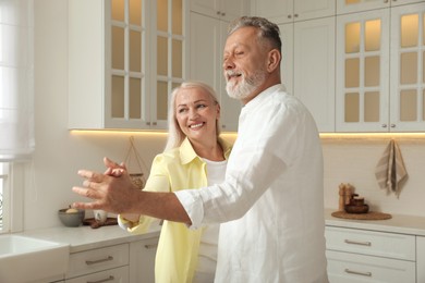 Photo of Happy senior couple dancing together in kitchen