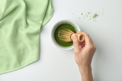 Woman preparing matcha tea at table, top view