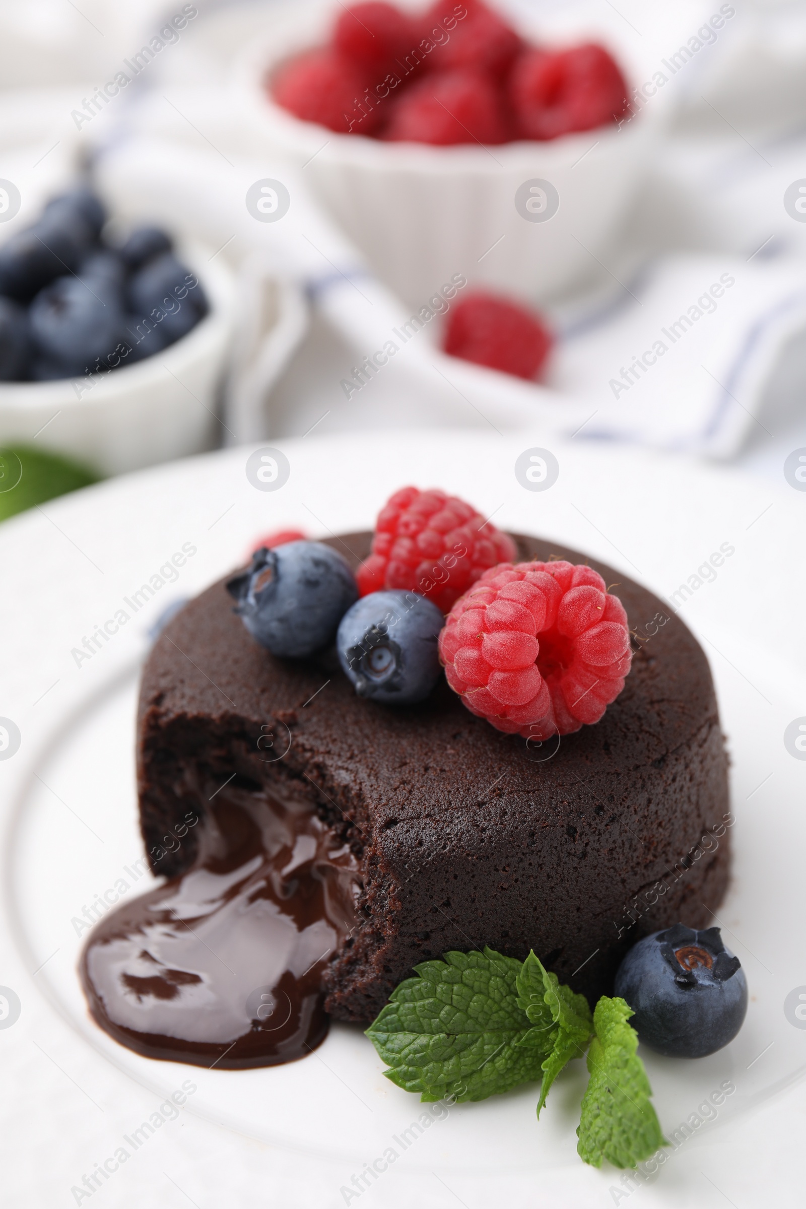 Photo of Delicious chocolate fondant, berries and mint on plate, closeup