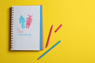 Phrase "SEX EDUCATION" written in notebook on yellow background, flat lay