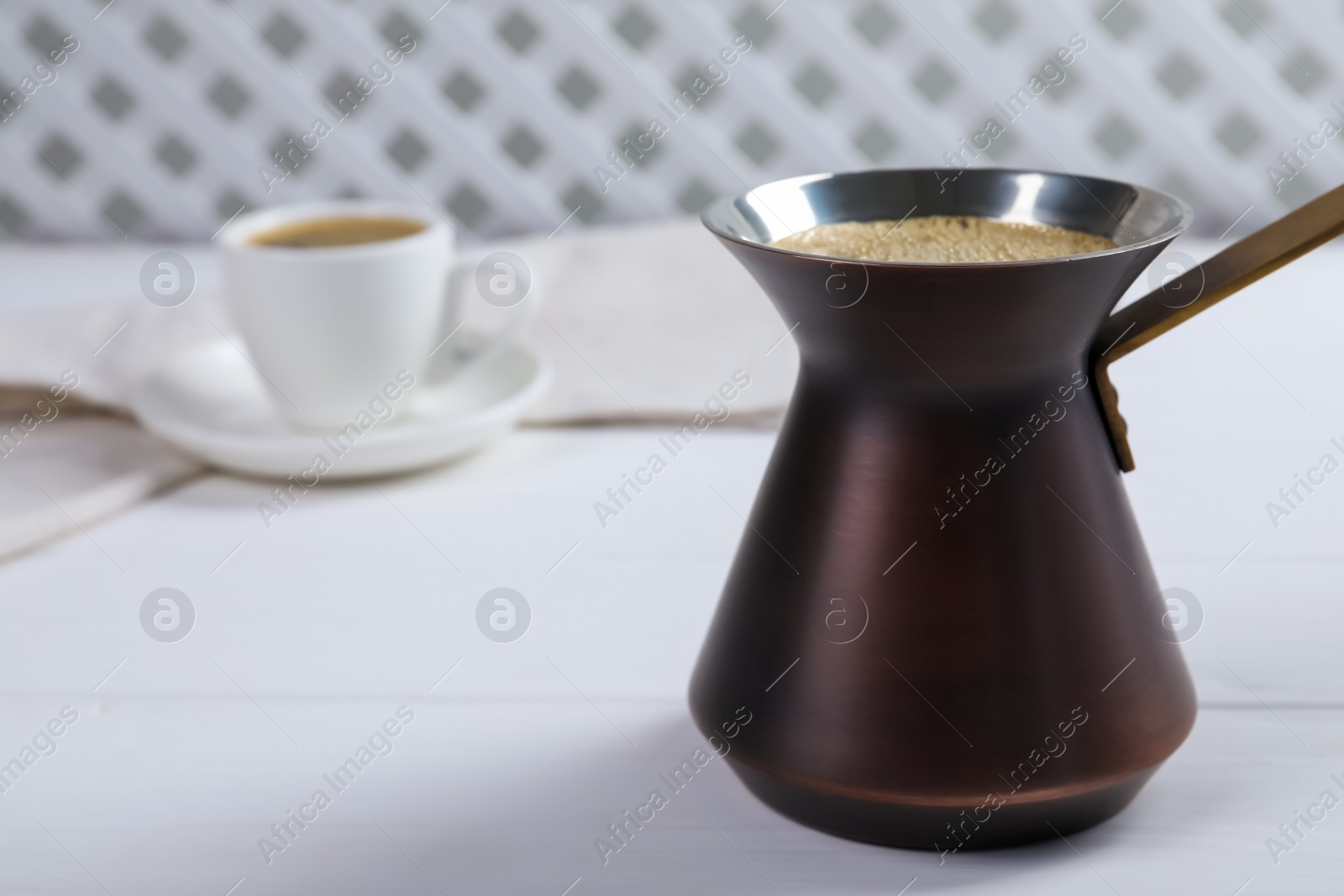 Photo of Turkish coffee pot with hot drink on white wooden table, space for text