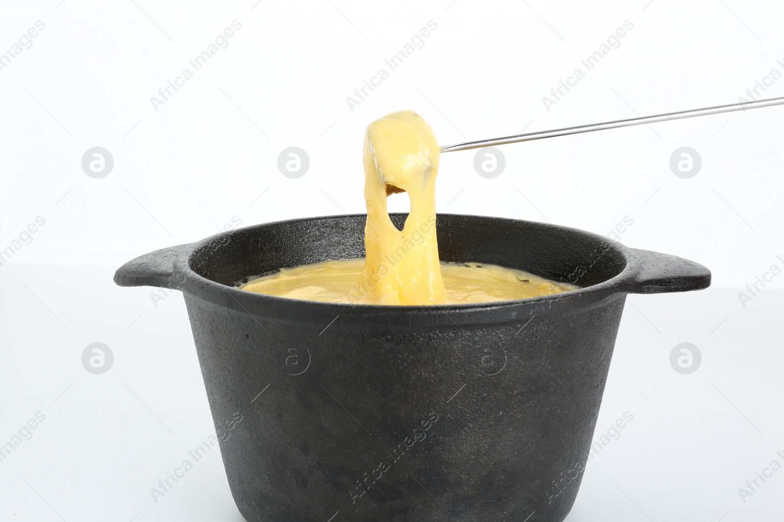 Photo of Dipping piece of bread into fondue pot with tasty melted cheese isolated on white