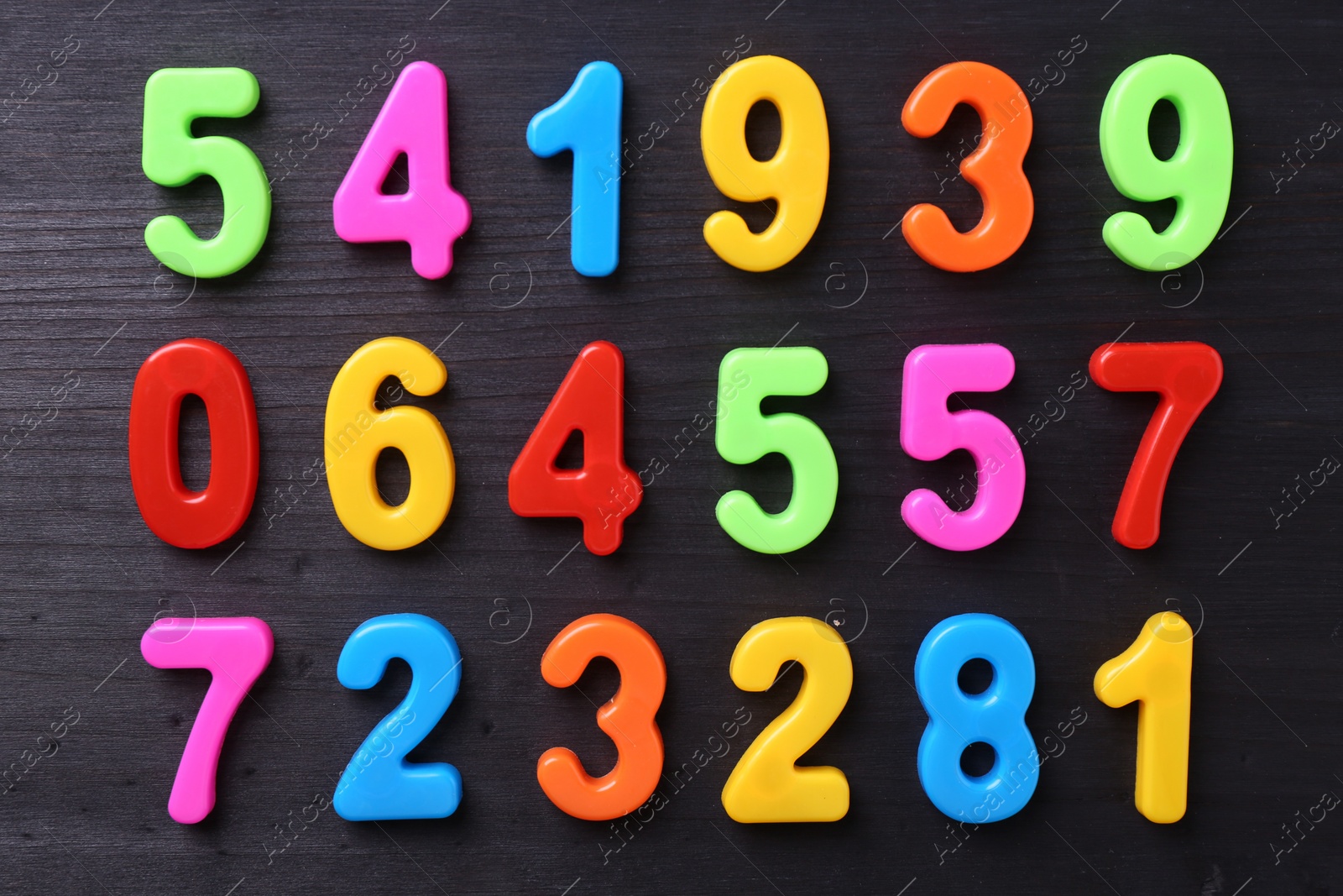 Photo of Colorful numbers on dark wooden school desk, flat lay