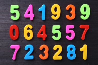 Colorful numbers on dark wooden school desk, flat lay