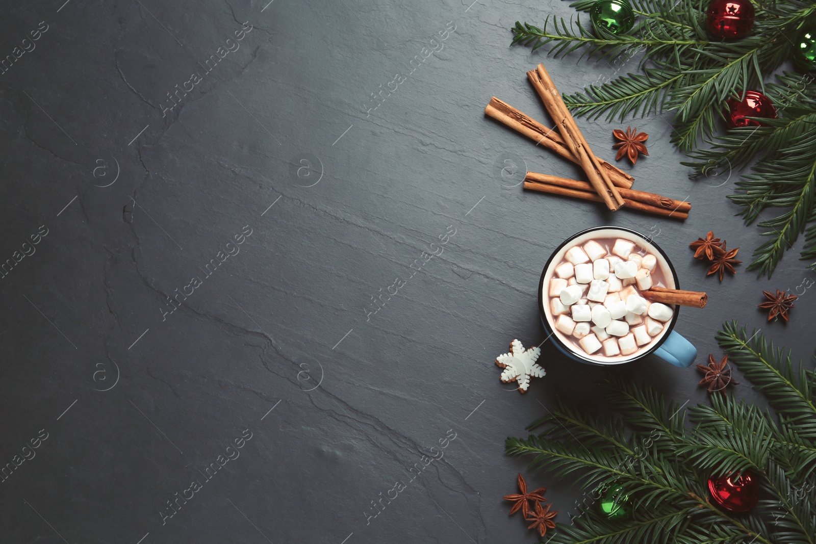 Photo of Delicious hot chocolate with marshmallows and Christmas decor on black table, flat lay. Space for text