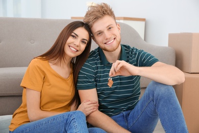 Young couple with key from their new house indoors. Moving day