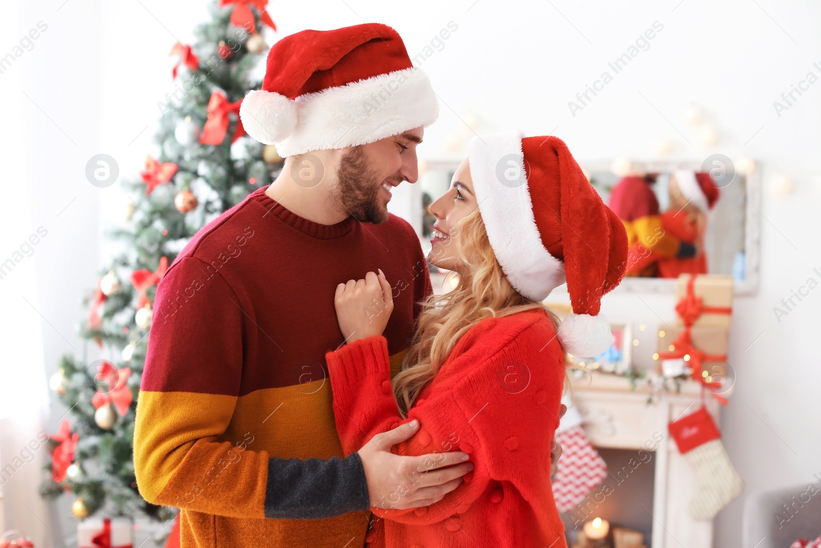 Photo of Young couple in Santa hats at home. Christmas celebration