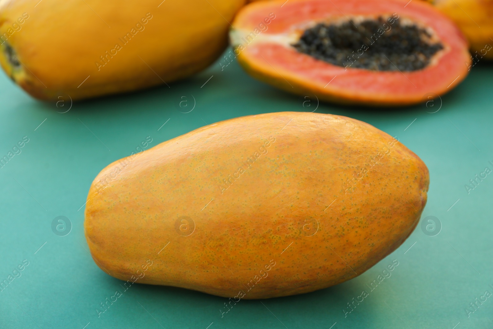 Photo of Fresh ripe cut and whole papaya fruits on light blue background, closeup