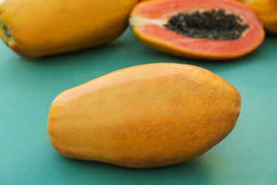 Fresh ripe cut and whole papaya fruits on light blue background, closeup