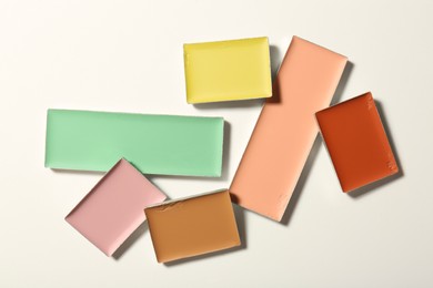 Different color correcting concealers on white background, top view