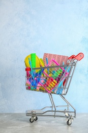 Photo of Small shopping cart with different school stationery on table