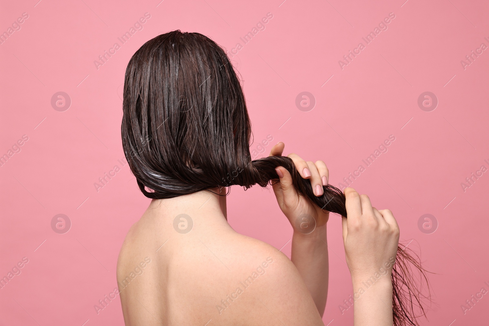 Photo of Woman applying hair mask on pink background