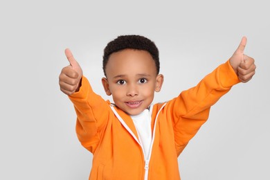 Photo of African-American boy showing thumbs up on light grey background