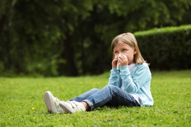 Photo of Little girl suffering from seasonal spring allergy on green grass in park