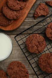 Delicious chocolate chip cookies and glass of milk on wooden table, flat lay