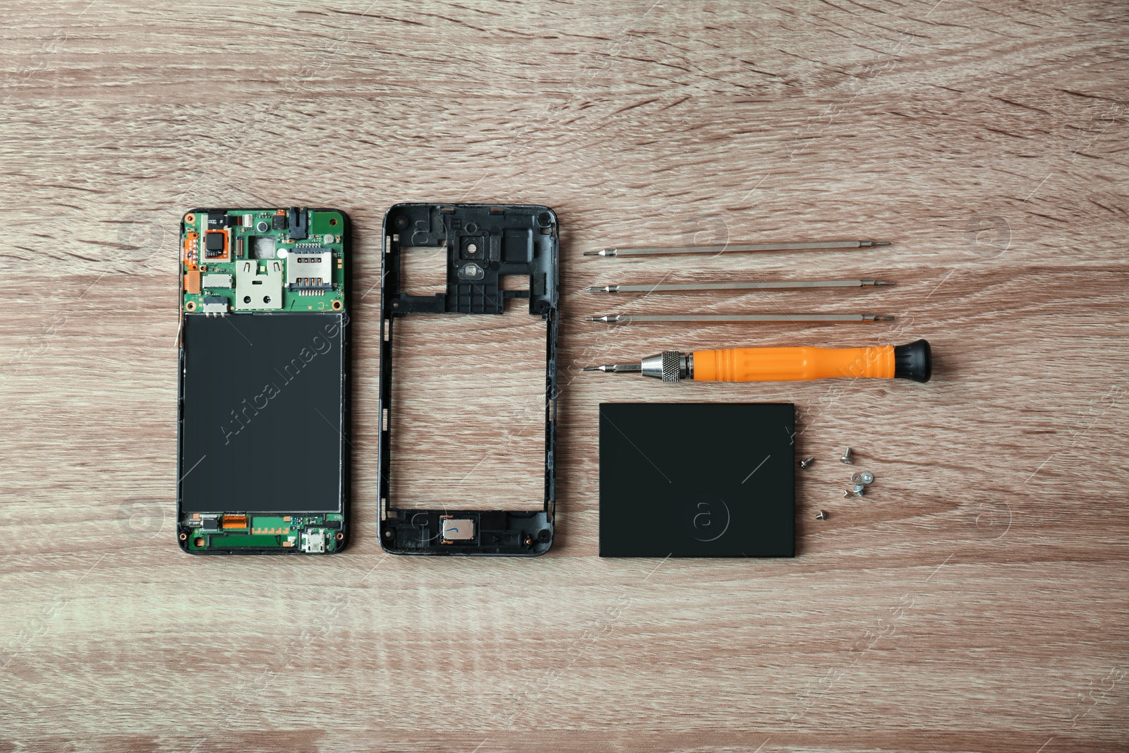 Photo of Flat lay composition with disassembled mobile phone and tools on wooden table. Repairing service
