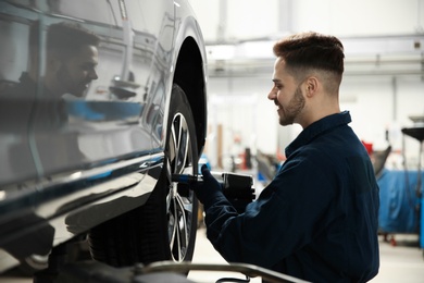 Photo of Technician working with car in automobile repair shop