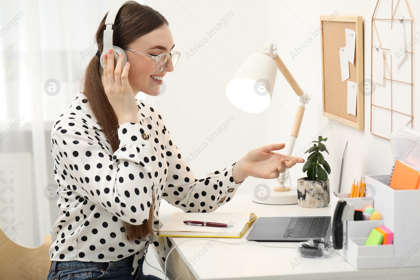 Photo of E-learning. Young woman using laptop during online lesson at table indoors