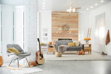Photo of Cozy living room interior with comfortable furniture, guitar and autumn decor