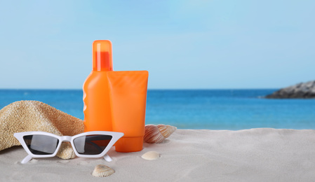 Image of Set of sun protection products and stylish sunglasses on sandy beach. Space for text