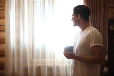 Photo of Man with drink near window indoors. Lazy morning