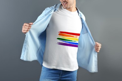 Image of Young man white wearing t-shirt with image of LGBT pride flag on grey background