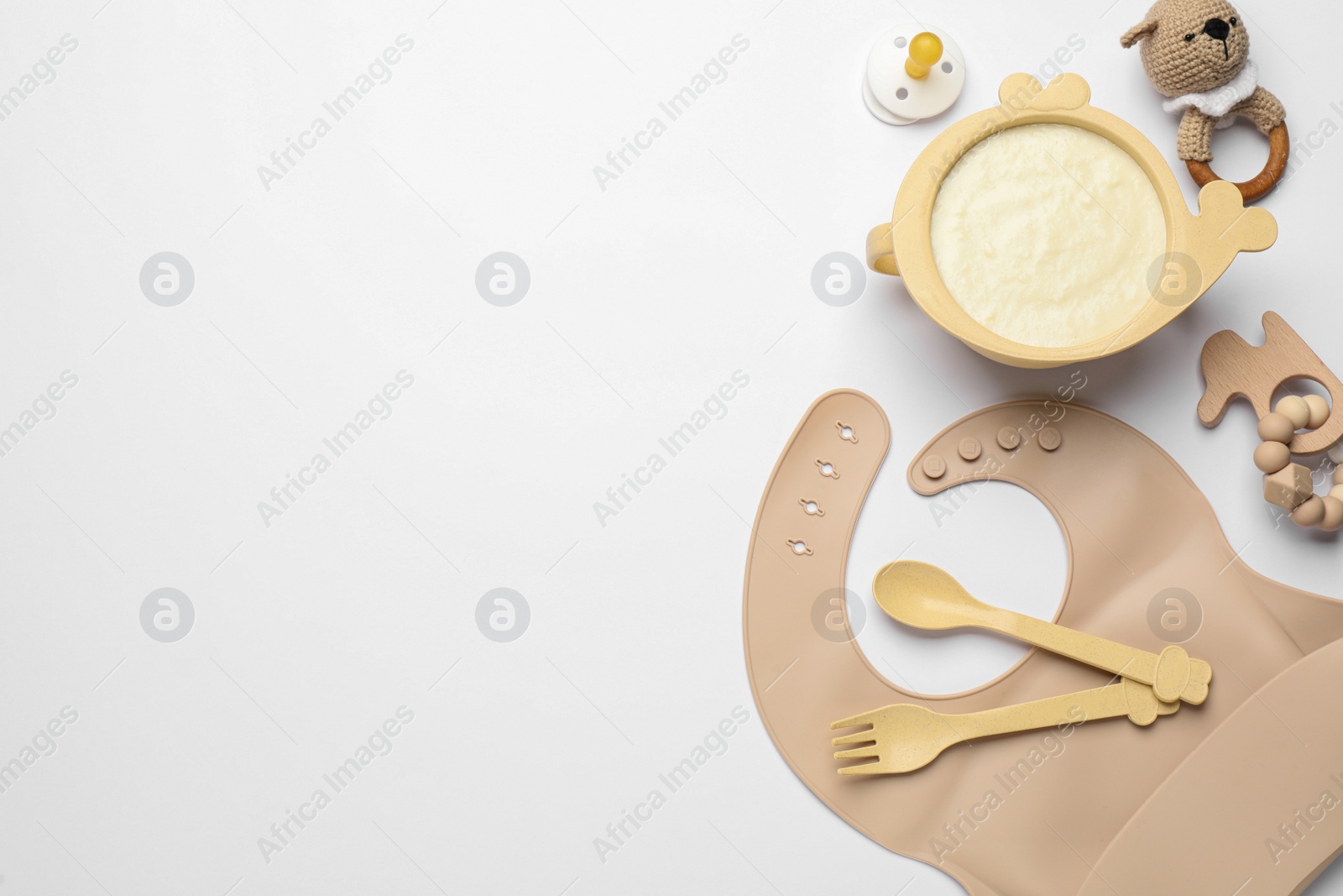 Photo of Healthy baby food in bowl and accessories on white background, top view. Space for text