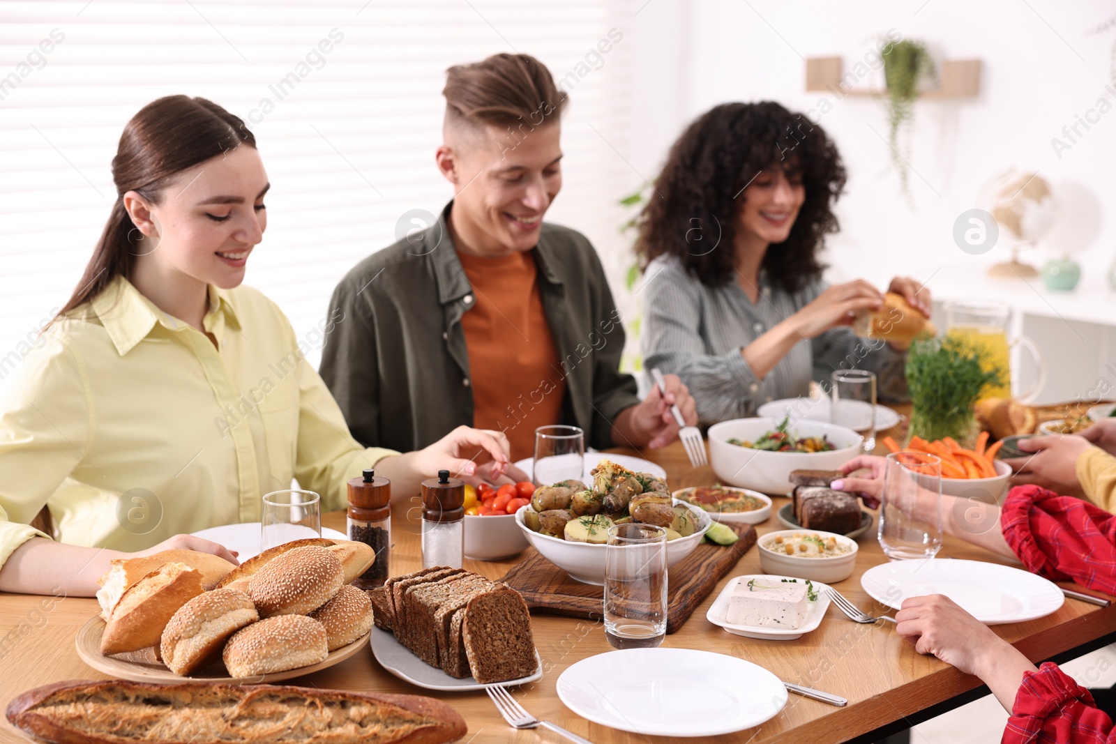 Photo of Friends eating vegetarian food at wooden table indoors