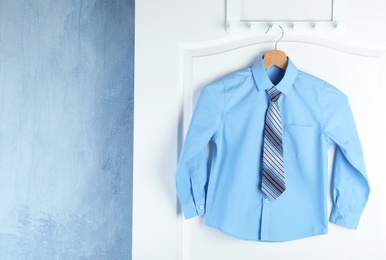 Shirt with tie on hanger indoors, space for text. School uniform