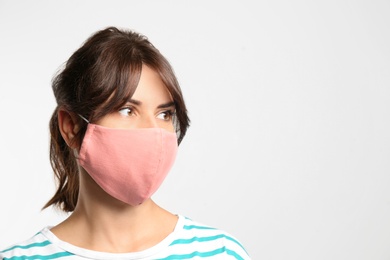 Photo of Young woman in protective face mask on light background, space for text