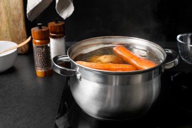 Photo of Boiling carrot and potatoes in pot on electric stove. Cooking vinaigrette salad