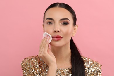 Photo of Beautiful woman removing makeup with cotton pad on pink background