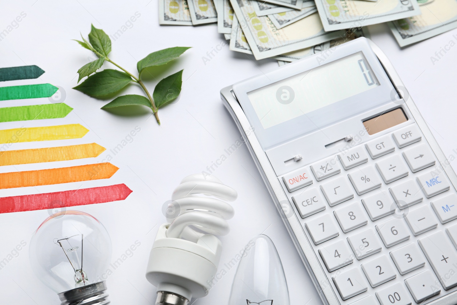 Photo of Composition with energy efficiency rating chart, light bulbs and calculator on white background