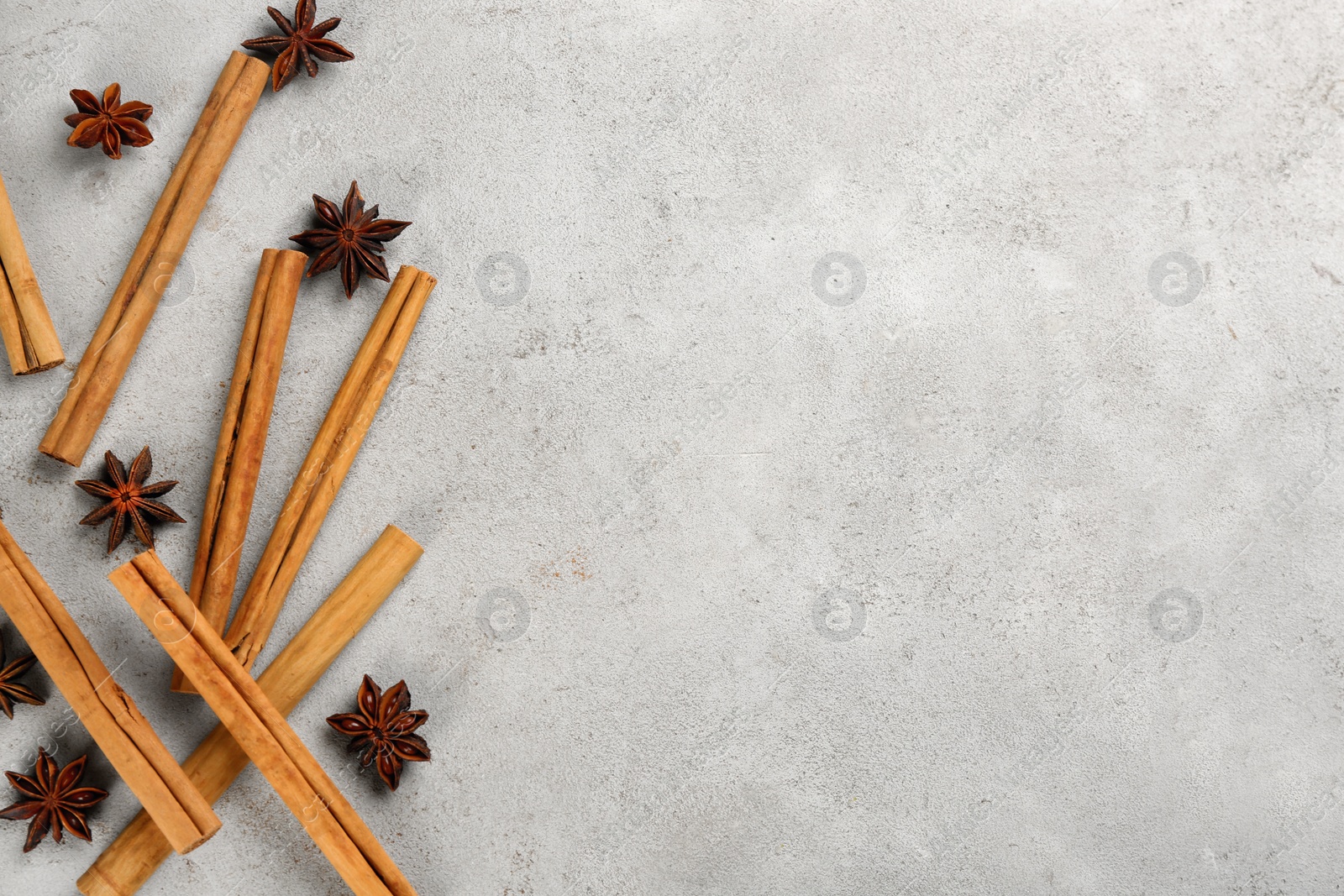 Photo of Aromatic cinnamon sticks and anise on light grey table, flat lay. Space for text