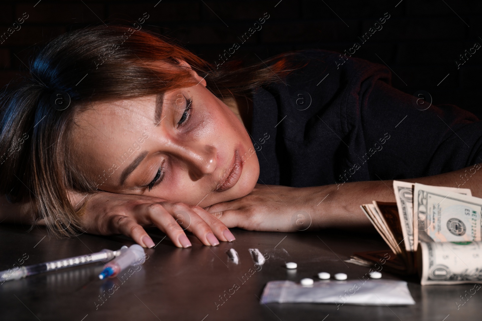 Photo of Addicted woman at table with different drugs