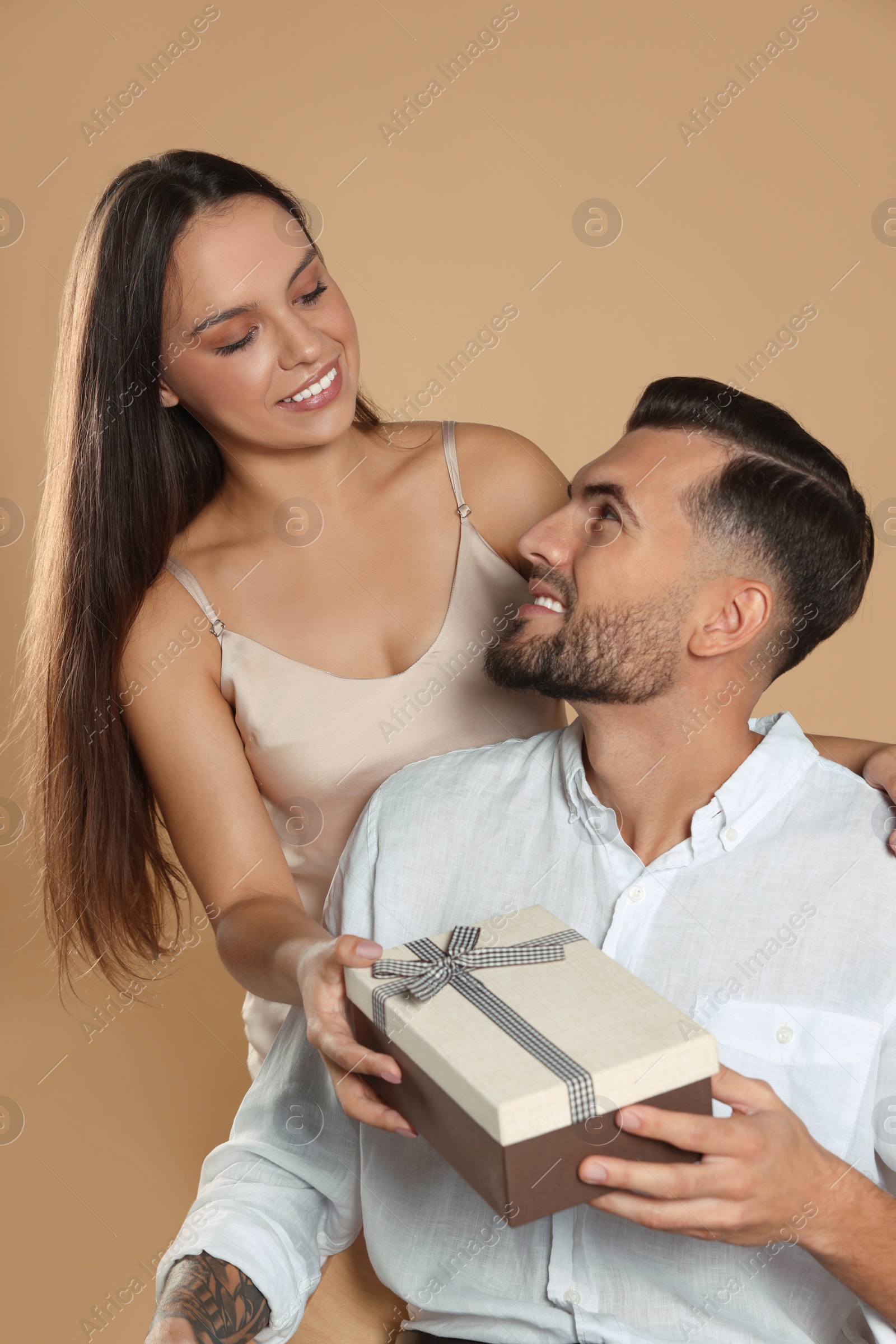 Photo of Lovely couple with gift on beige background