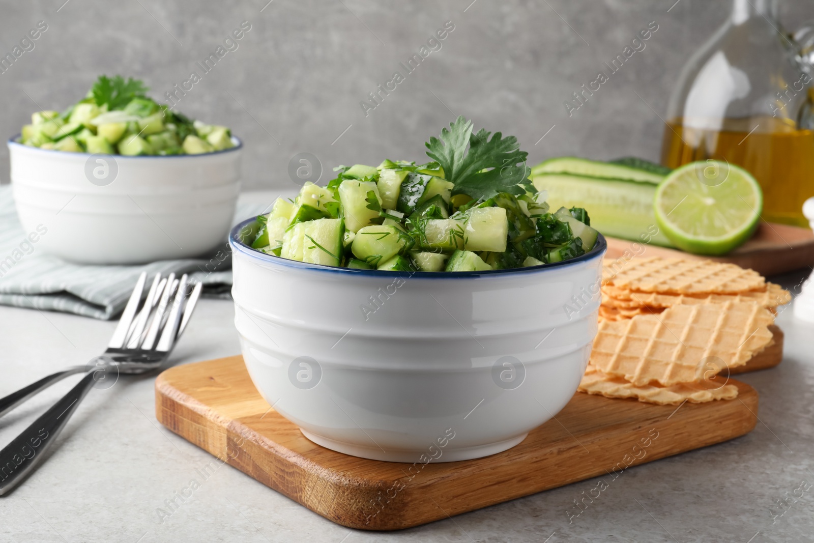 Photo of Bowl of delicious cucumber salad served on light table