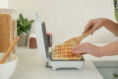 Woman making delicious Belgian waffles in kitchen, closeup