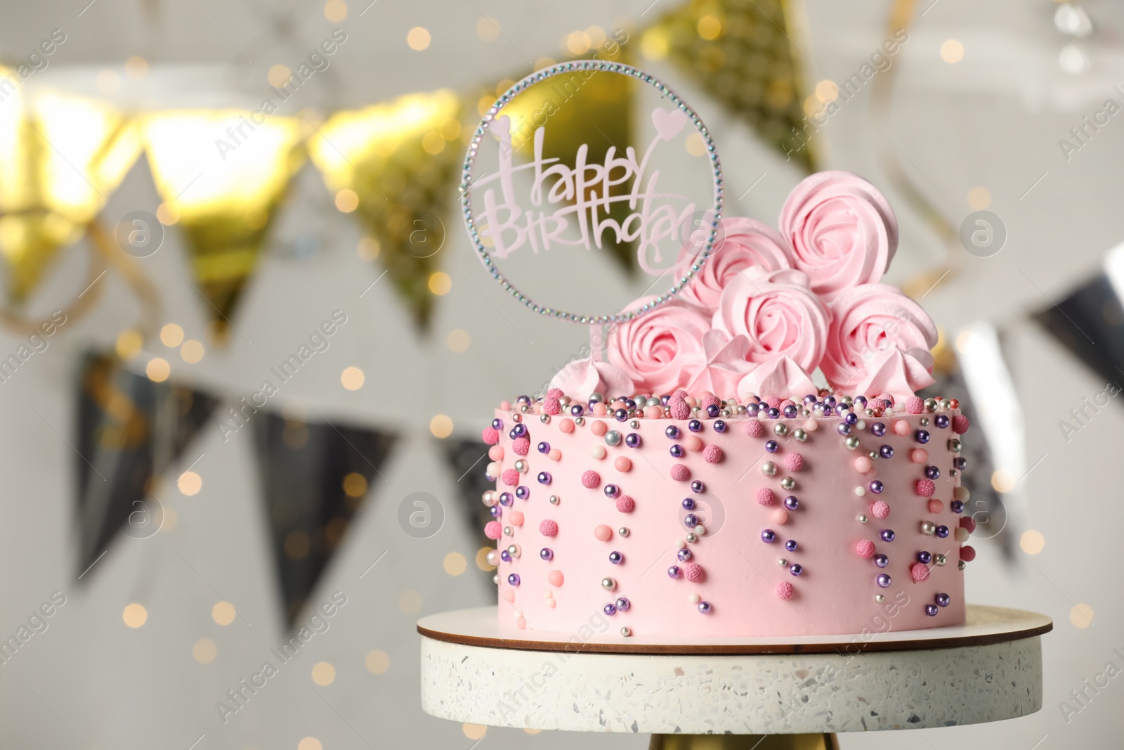 Photo of Beautifully decorated birthday cake on stand against blurred festive lights. Space for text