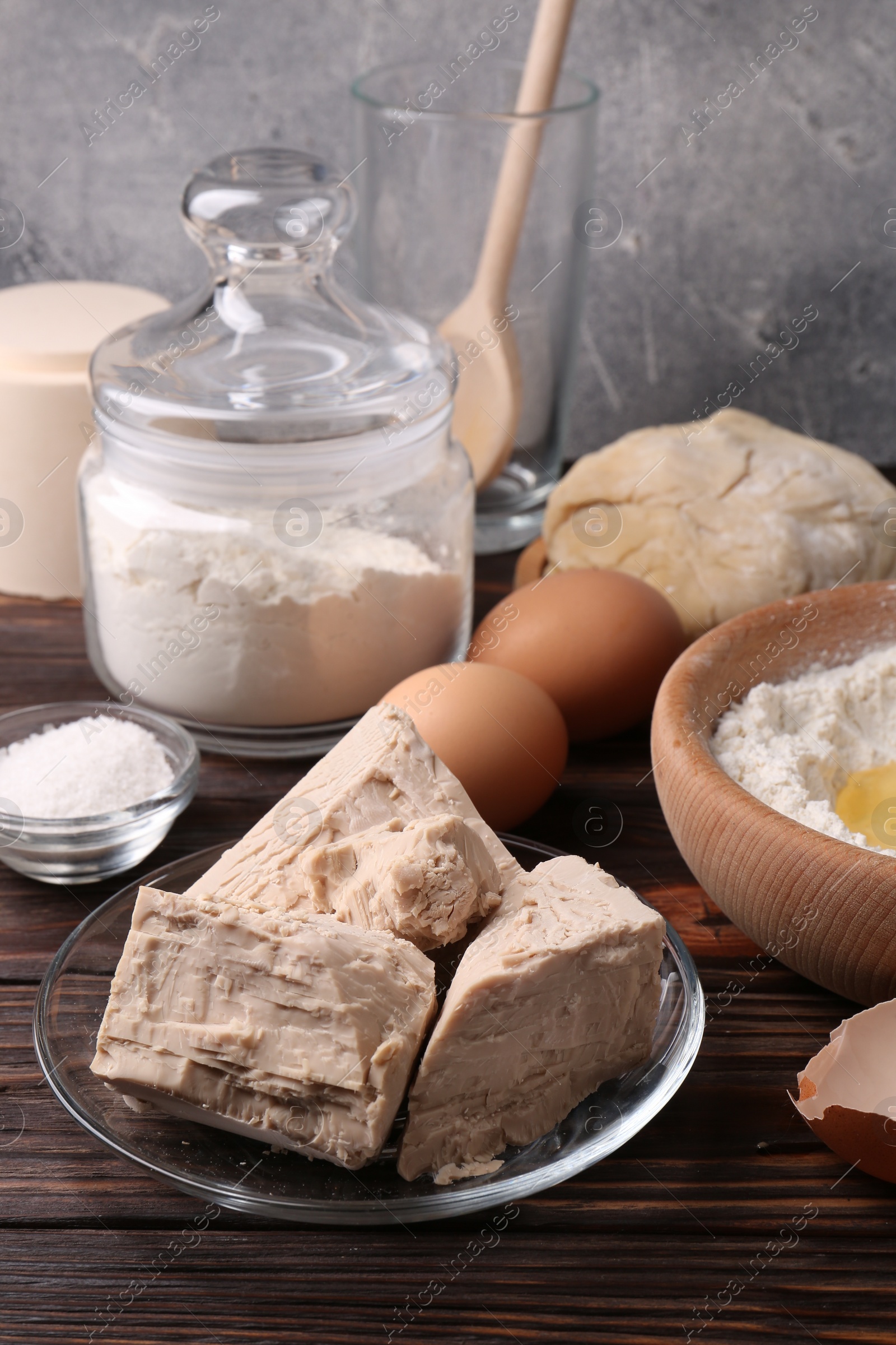 Photo of Compressed yeast, flour, salt, dough and eggs on wooden table
