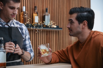 Young man with glass of whiskey in bar