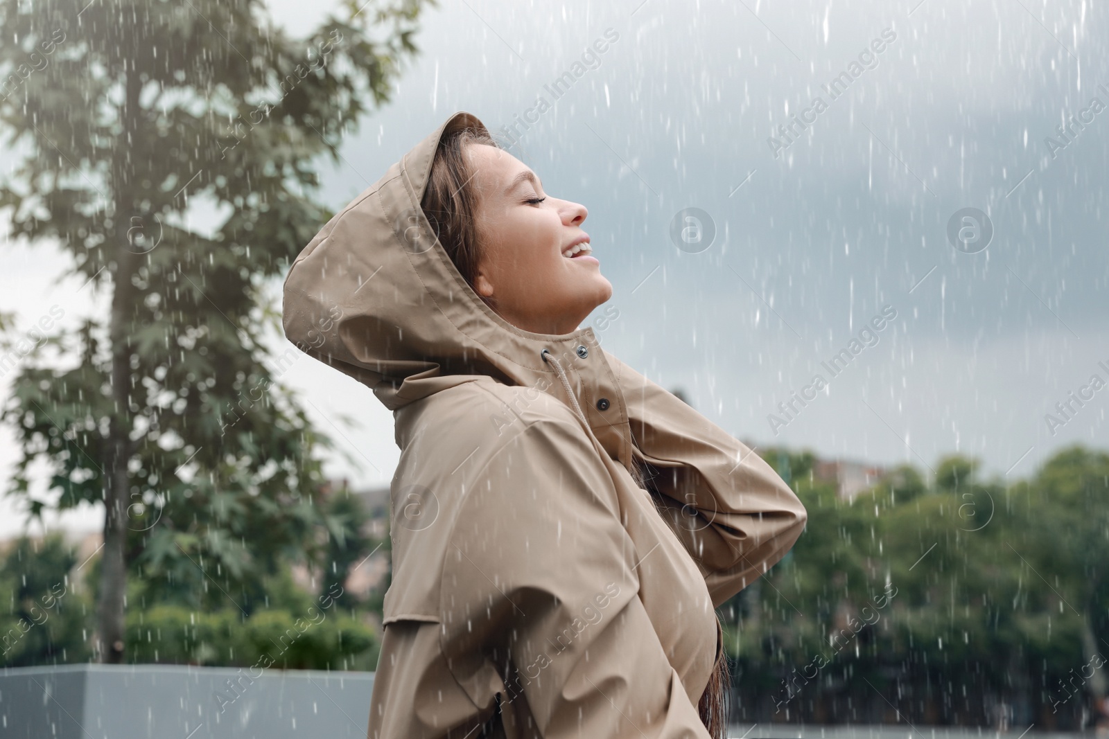Photo of Woman with raincoat walking under rain in park