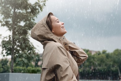 Woman with raincoat walking under rain in park