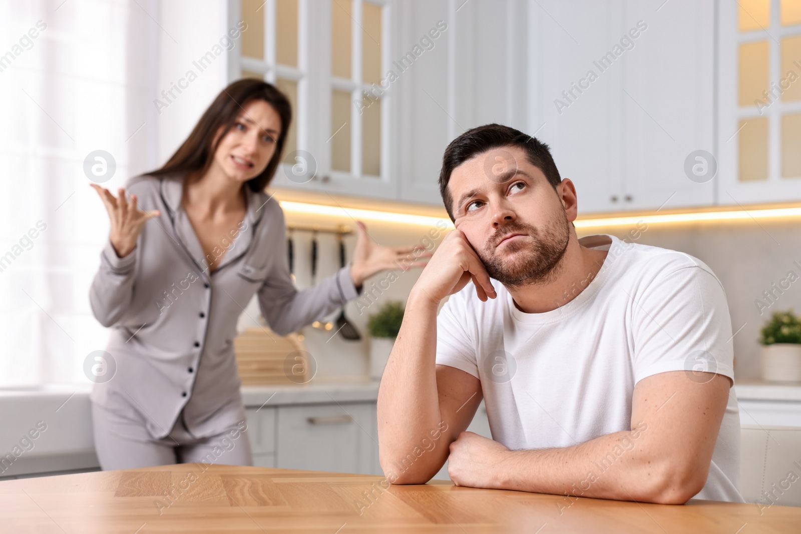 Photo of Husband ignoring his wife in kitchen, selective focus. Relationship problems