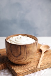 Photo of Wooden bowl with creamy yogurt served on table. Space for text