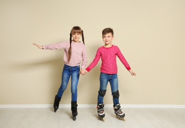 Photo of Cute boy and girl with roller skates near color wall