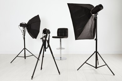 Empty chair in front of camera and professional lighting equipment indoors. Photo studio set