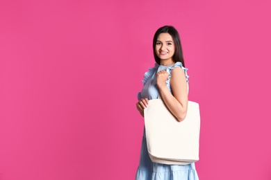 Beautiful young woman with stylish blank eco bag against color background, space for text
