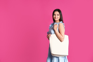 Photo of Beautiful young woman with stylish blank eco bag against color background, space for text