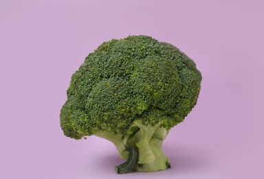 Photo of Fresh raw green broccoli on violet background